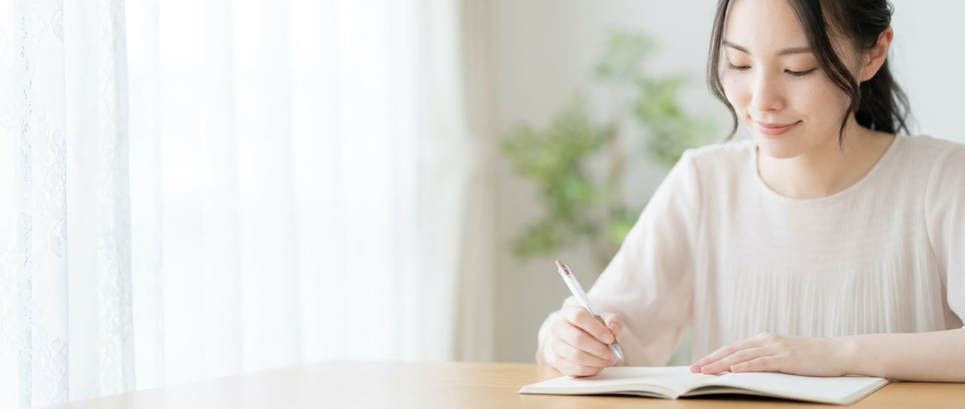 明るい窓辺でノートを書き終え、穏やかに微笑む女性